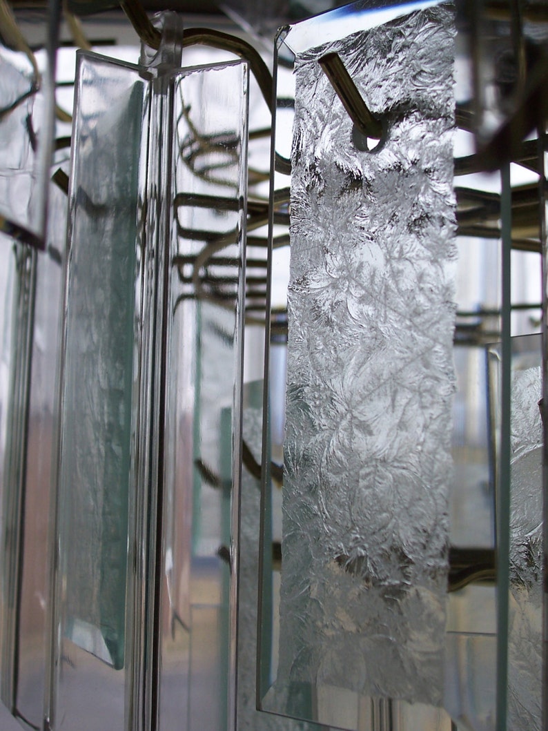 May include: Close-up of a crystal chandelier with multiple clear glass prisms hanging from a metal frame.