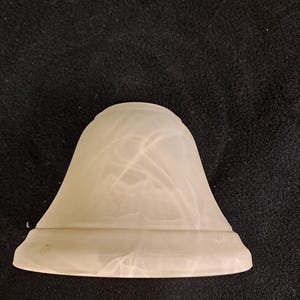Op de afbeelding: Een witte albasten lampenkap met een swirl-patroon.