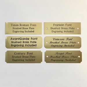 May include: Six gold-colored metal plates with different font styles. Each plate has the font name, "Brushed Brass Plate", and "Engraving Included" printed on it.