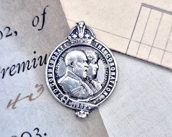 Könnte beinhalten: Silberne Gedenkmedaille mit einem Porträt von König Edward VII. und Königin Alexandra. Die Medaille trägt die Inschrift "To Commemorate The Coronation 1902".