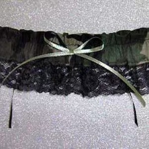 Puede incluir: Una liga de camuflaje verde y negro con un lazo de sat&eacute;n blanco y ribete de encaje negro.