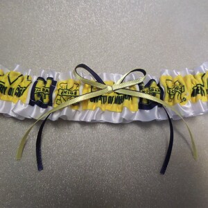May include: White satin garter with yellow and blue fabric accents. The fabric accents feature the University of Michigan logo and the text "University of Michigan".