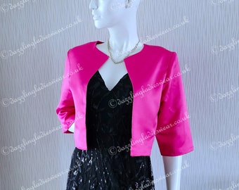May include: A hot pink bolero jacket with a V-neckline and three-quarter sleeves. The jacket is made of a smooth, satin-like fabric.