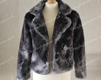 May include: A gray faux fur jacket with a collar and a cropped length. The jacket is on a mannequin.