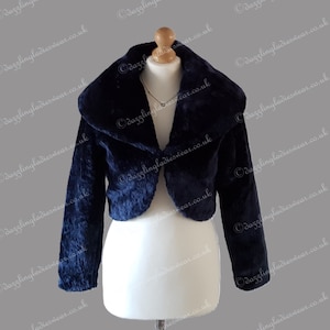 Puede incluir: Bolero de piel sintética azul marino con cuello ancho y mangas largas. La chaqueta corta se muestra en un maniquí. La imagen tiene el texto "dazzlingladieswear.co.uk" repetido.