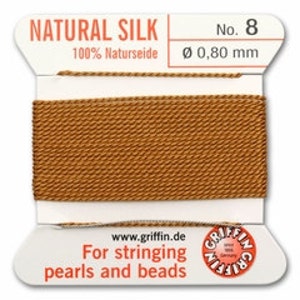 May include: A spool of natural silk thread, color #8, with a diameter of 0.80 mm. The label reads "NATURAL SILK" and "100% Naturseide". The text "For stringing pearls and beads" is also visible.