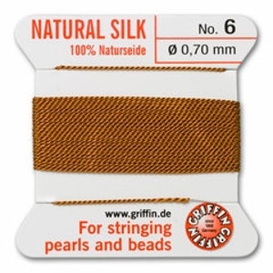May include: A spool of natural silk thread, color number 6, with a diameter of 0.70 mm. The label reads "NATURAL SILK" and "100% Naturseide". The text "For stringing pearls and beads" is also visible.
