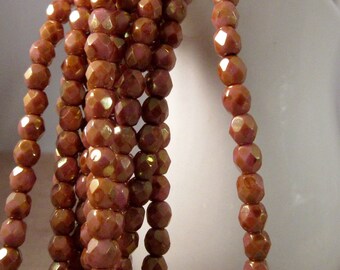 May include: Strands of faceted beads in shades of brown and pink. The beads have a metallic sheen, catching the light. The beads are strung together, creating a cascading effect. Ideal for jewelry making or craft projects.