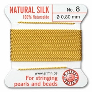 May include: A spool of natural silk thread, labeled "NATURAL SILK" and "No. 8". The thread is a golden yellow color, with a diameter of 0.80 mm. Text on the label reads "For stringing pearls and beads."