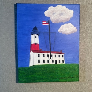 Puede incluir: Una pintura sobre lienzo que representa un faro blanco y rojo con una linterna negra, situado sobre una colina de hierba verde bajo un cielo azul con dos nubes blancas. Un mástil alto con una bandera estadounidense está junto al faro.