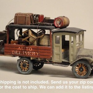 May include: A miniature antique delivery truck with the words "AUTO DELIVERY" on the side. The truck is painted in shades of brown, green, and grey, with a detailed interior and cargo on top. The wheels are brown and the truck has a vintage aesthetic.