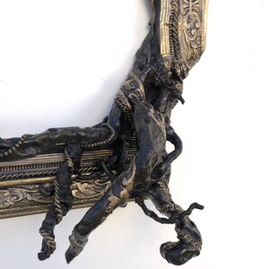 May include: An ornate picture frame in dark bronze with gold highlights. The frame has a textured, organic design with twisted elements and intricate detailing, creating a unique, artistic aesthetic.