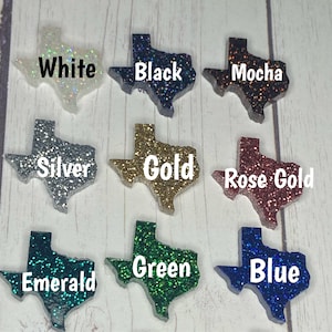 May include: Nine different colors of glitter Texas-shaped ornaments. The colors are white, black, mocha, silver, gold, rose gold, emerald, green, and blue.