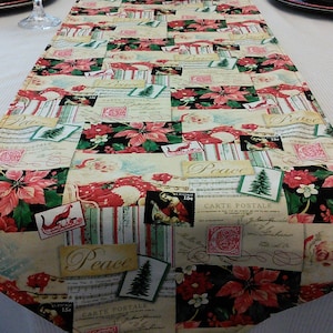 May include: A Christmas-themed table runner with a patchwork design featuring red poinsettias, green pine branches, and vintage-style postcards with the words "Peace" and "Carte Postale".