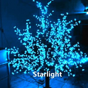 May include: A blue LED light-up tree with a black base. The tree is decorated with small white lights that resemble blossoms. The text "Starlight" is visible on the base of the tree.