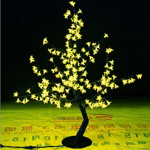 May include: A decorative artificial tree with a black trunk and branches covered in small yellow LED lights, resembling a cherry blossom tree.