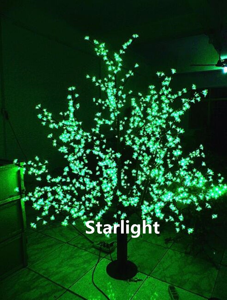 May include: A green LED light-up tree with a black base. The tree is decorated with small green lights that resemble blossoms. The text "Starlight" is visible on the base of the tree.