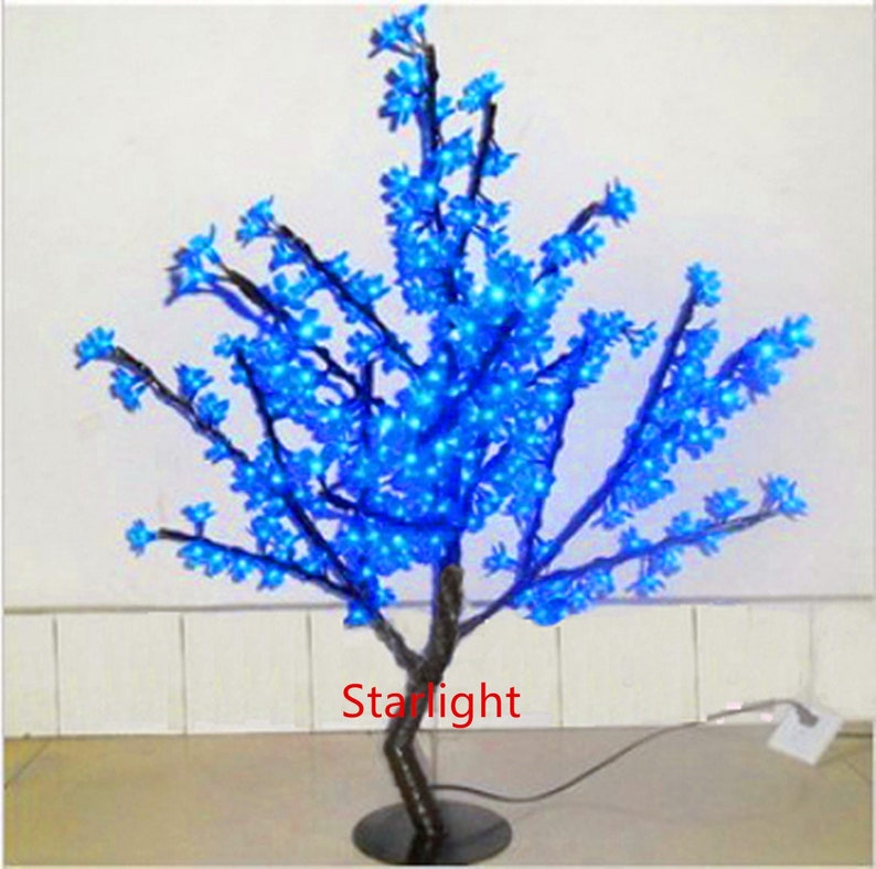 May include: A blue LED light-up cherry blossom tree with a black base and a cord. The tree is decorated with blue lights that resemble blossoms.