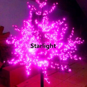 May include: A pink LED light-up tree with a black metal base. The tree is decorated with small pink lights that resemble blossoms. The text "Starlight" is visible on the tree.