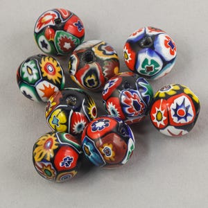 May include: A collection of colorful glass beads with intricate floral and geometric patterns. The beads feature a variety of colors, including red, blue, yellow, green, and white. Each bead has a hole for stringing, perfect for jewelry making or crafting projects.