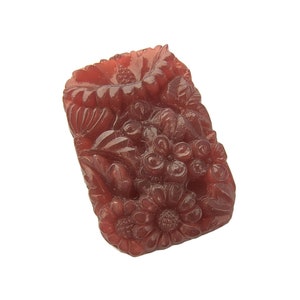 May include: A carved, reddish-brown, floral design pendant. The pendant is made of plastic and has a detailed floral pattern.
