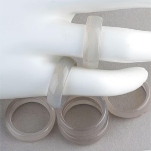 May include: Set of four gray agate rings. The rings are stacked on top of each other. The rings are made of natural stone and have a smooth, polished finish.