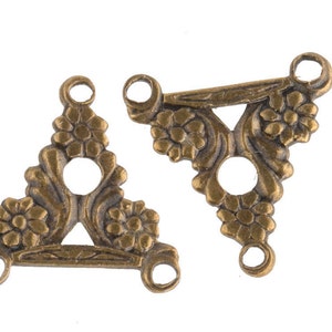 May include: Two antique gold-toned metal triangle-shaped connector charms with floral designs and three holes each.