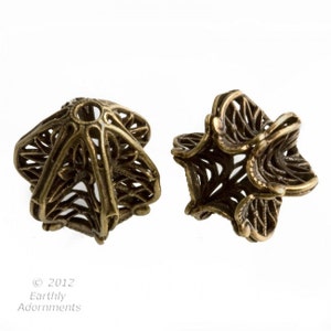 May include: Two antique gold metal filigree beads with a starburst design. The beads are hollow and have a small hole in the center for stringing.