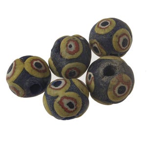 May include: Six round glass beads with a blue background and yellow, red and black eye designs.