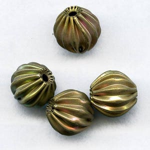 May include: Four gold-coloured glass beads with a ribbed texture. The beads are round and have a slightly iridescent finish.
