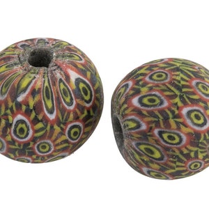 May include: Two round glass beads with a colourful, intricate pattern of red, yellow, black, and white. The beads have a hole in the centre for stringing.