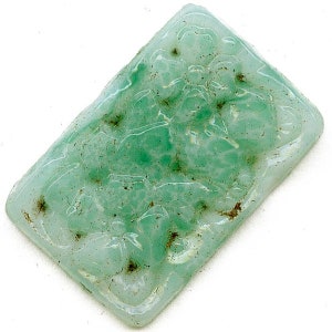 May include: A light green jade pendant with a carved design. The pendant is rectangular in shape and has a smooth, polished surface.