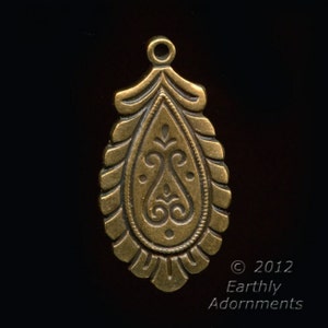 May include: A gold-toned metal pendant with an ornate design. The pendant is shaped like a teardrop and features a detailed floral pattern.