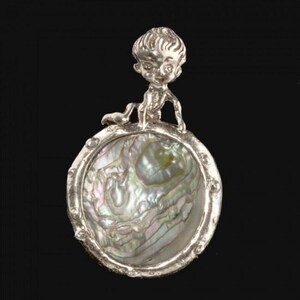 May include: A silver pendant featuring a small, detailed figurine of a person standing on a round, iridescent abalone shell.