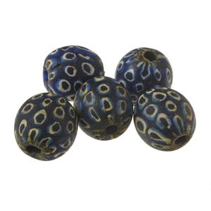 May include: Five blue glass beads with a white and black pattern. The beads are oval shaped and have a hole in the centre.
