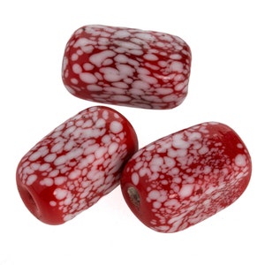 May include: Three red and white speckled glass beads. The beads are oval shaped and have a mottled appearance.
