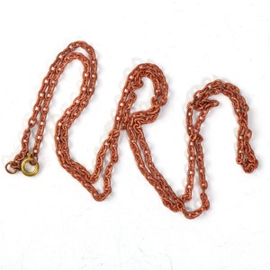May include: A copper chain necklace with a lobster clasp. The chain is made of small, linked circles.