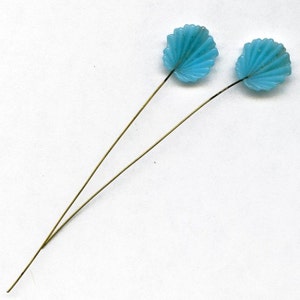 May include: Two blue glass flower accents on gold wire stems. The flower accents are shaped like seashells.