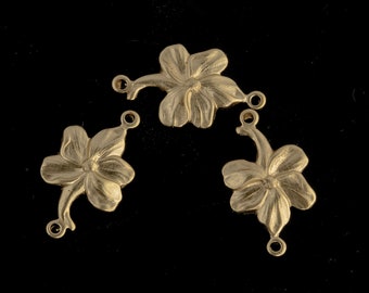 Könnte beinhalten: Drei goldfarbene Metall-Blumenanhänger mit Ösen zum Anbringen an Schmuck oder andere Bastelarbeiten. Jeder Anhänger zeigt ein Design mit einer fünfblättrigen Blume.