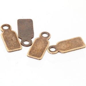 May include: Four antique gold-toned metal tags with a hole at the top for hanging. The tags are rectangular and have a slightly textured surface.