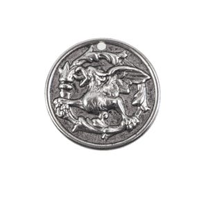 May include: A round, silver-colored pendant with a detailed relief of a mythical griffin holding a torch, surrounded by ornate floral elements. The pendant has a small hole at the top for stringing.
