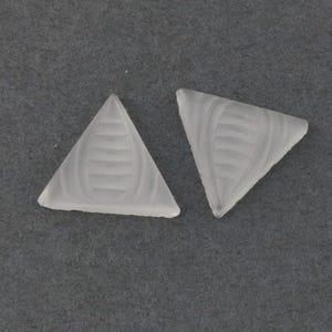May include: Two white glass triangle-shaped beads with a textured design.