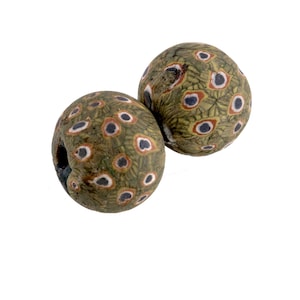 May include: Two round glass beads with a green, white, and black eye pattern. The beads are about 1 inch in diameter.