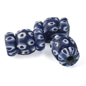 May include: Three blue and white glass beads with a geometric pattern. The beads are cylindrical and have a hole in the center.