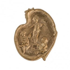 May include: A gold-colored metal ashtray with a heart-shaped design. The ashtray features a raised relief of three cherubs, one standing on a pedestal and two seated.
