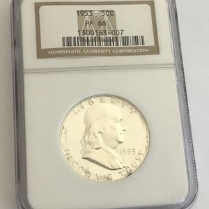 May include: A 1953 half dollar coin graded PF 66 by the Numismatic Guaranty Corporation. The coin is encased in a plastic slab with a white label.