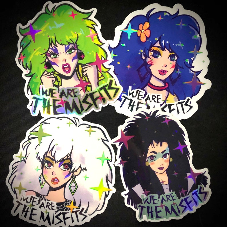 May include: Four holographic stickers featuring cartoon characters with colorful hair and the text "We Are The Misfits".