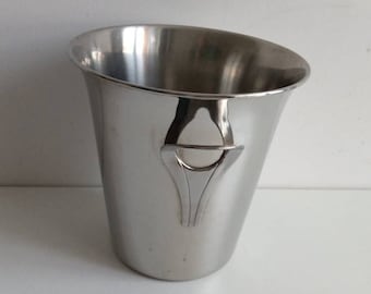 May include: A silver ice bucket with a decorative handle. The bucket is made of stainless steel and has a smooth, polished finish.