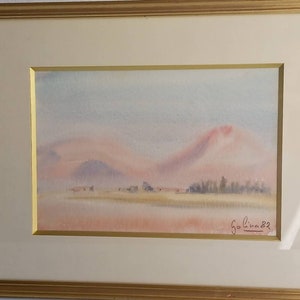 Framed and signed watercolour landscape painting of mountains.