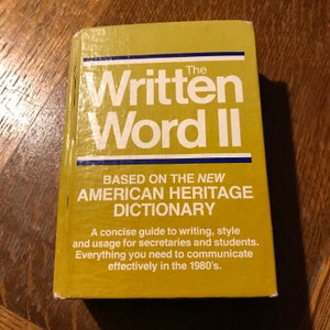 Op de afbeelding: Een geel boek getiteld "The Written Word II" gebaseerd op het New American Heritage Dictionary. Het boek is een beknopte gids voor schrijven, stijl en gebruik voor secretaresses en studenten. Het bevat alles wat je nodig hebt om effectief te communiceren in de jaren 1980.